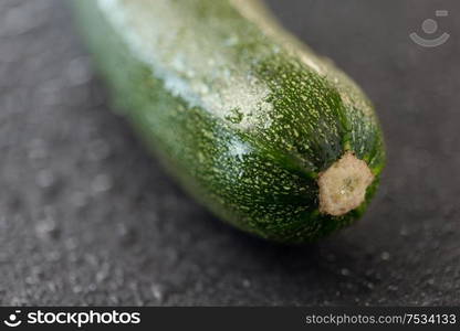 vegetable, food and culinary concept - close up of zucchini on slate stone background. zucchini on slate stone background