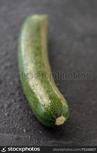 vegetable, food and culinary concept - close up of zucchini on slate stone background. zucchini on slate stone background