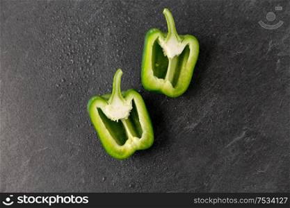 vegetable, food and culinary concept - cut green pepper on slate stone background. cut green pepper on slate stone background
