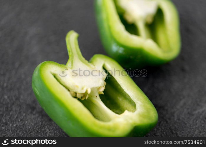 vegetable, food and culinary concept - cut green pepper on slate stone background. cut green pepper on slate stone background