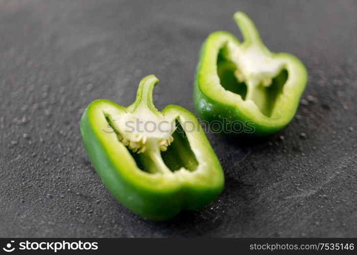 vegetable, food and culinary concept - cut green pepper on slate stone background. cut green pepper on slate stone background