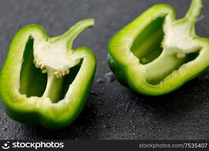 vegetable, food and culinary concept - cut green pepper on slate stone background. cut green pepper on slate stone background