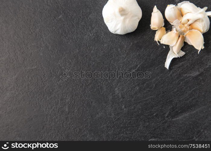 vegetable, food and culinary concept - garlic on slate stone background. garlic on slate stone background