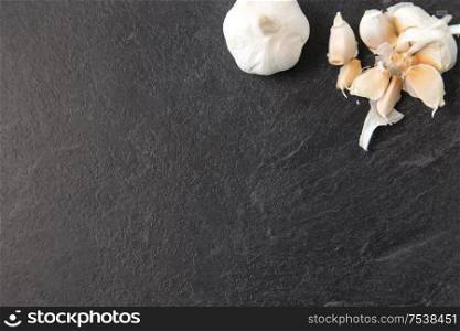 vegetable, food and culinary concept - garlic on slate stone background. garlic on slate stone background