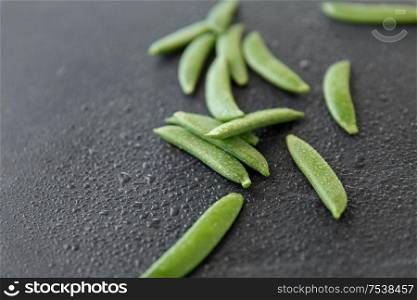 vegetable, food and culinary concept - peas on wet slate stone background. peas on wet slate stone background