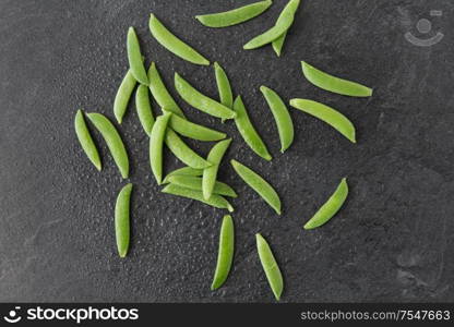 vegetable, food and culinary concept - peas on wet slate stone background. peas on wet slate stone background
