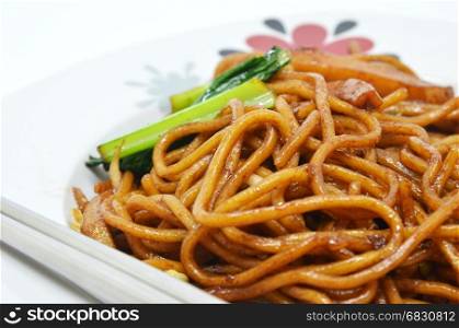 Vegetable fried noodle on white plate and chopstick