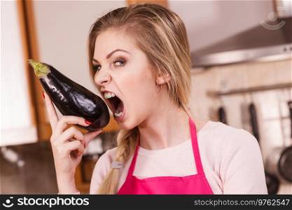 Vegetable having good impact on teeth. Young woman eating biting delicious eggplant.. Woman holding biting eggplant.