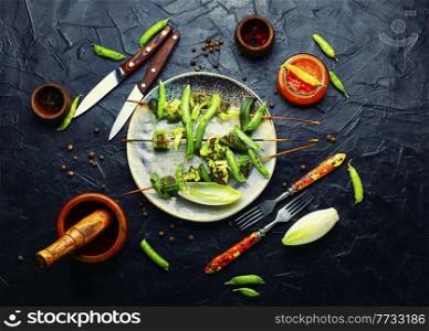Vegetable kebab with broccoli, green peas and okra.Roasted vegetables on a skewer. Vegetarian skewer and hot sauce