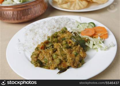 Vegetable korma curry with a raw vegetable salad, white rice and poppadums.