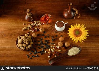 Vegetable oil in bottles, healthy seeds and nuts on old wooden floor