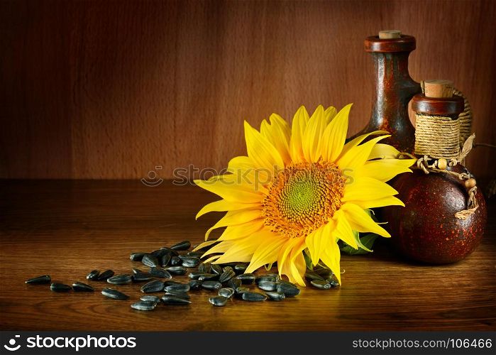 Vegetable oil in ceramic ware and sunflower seeds on wooden background. Healthy food. Free space for text.