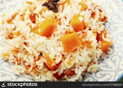 Vegetable pilaf on a plate, rice with pumpkin. Stewed rice with pumpkin