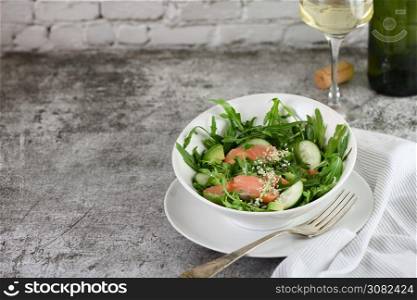 Vegetable salad from arugula, avocado and cucumber pieces with the addition of tender salted salmon, seasoned sesame seeds