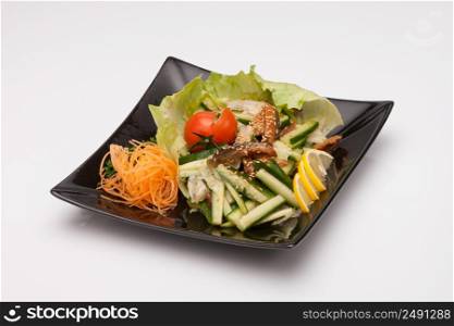 Vegetable salad in black square plate on a light background. vegetable salad in a black plate on a light background