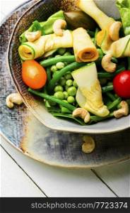 Vegetable salad of zucchini, asparagus beans, peas, tomatoes and nuts. Diet spring salad.. Healthy fresh vegetable salad