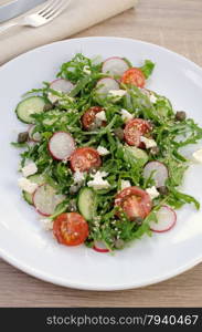 Vegetable salad with arugula, feta ,olive dressing and sesame seeds