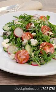 Vegetable salad with arugula, feta ,olive dressing and sesame seeds