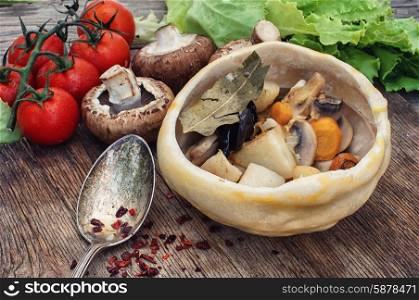 vegetable stir-fry recipe traditional Ukrainian cuisine. mushrooms baked with potatoes in bread pot amid onion and tomato
