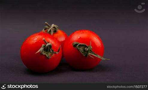 vegetable, three cherry tomatoes on a dark background close-up.