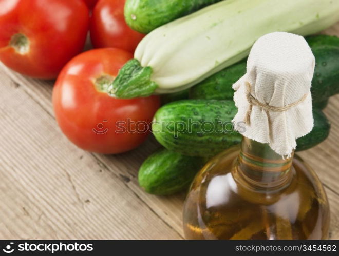 vegetables and a bottle of oil, still life on a wooden table