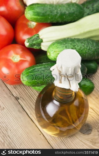 vegetables and a bottle of oil, still life on a wooden table