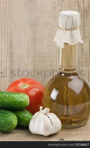 vegetables and a bottle of oil, still life on a wooden table