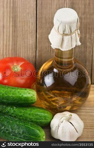 vegetables and a bottle of oil, still life on a wooden table