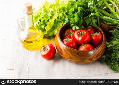 Vegetables and olive oil on the white wooden background. Healthy eating background. Detox or vegetarian food concept with fresh vegetables.. Vegetables and olive oil on the white wooden background