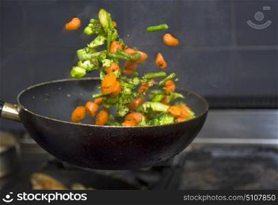 Vegetables flying mid air, being flipped from a frying pan