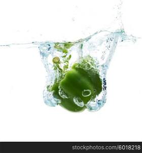 vegetables, food and healthy eating concept - close up of fresh green pepper falling or dipping in water with splash over white background