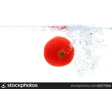 vegetables, food and healthy eating concept - close up of red fresh tomato falling or dipping in water with splash over white background