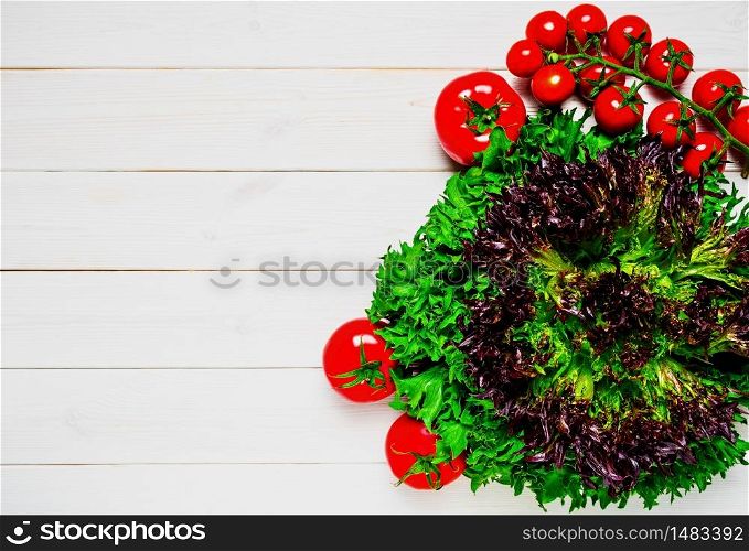 Vegetables for food, green fresh salad bio, ripe cherry tomatoes on a white wooden background. Variety of healthy vegetables, harvesting. Copy space for text