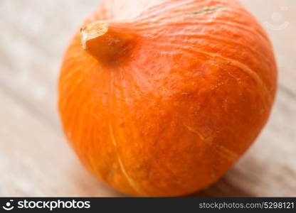 vegetables, harvest and halloween concept - close up of pumpkin on wooden table. close up of pumpkin on wooden table