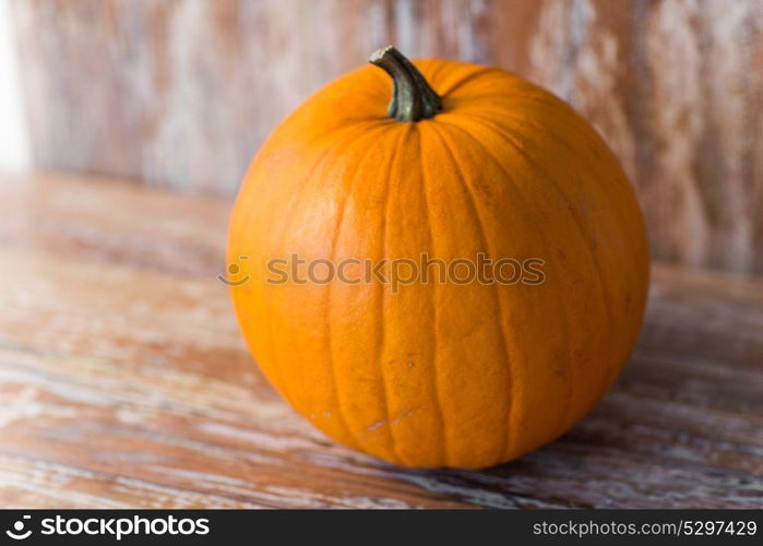 vegetables, harvest and halloween concept - ripe pumpkin on wooden table. ripe pumpkin on wooden table