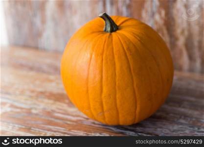 vegetables, harvest and halloween concept - ripe pumpkin on wooden table. ripe pumpkin on wooden table