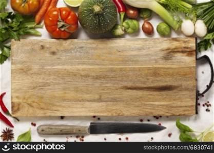 Vegetables, herbs, spices and empty cutting board. Top view. Space for text