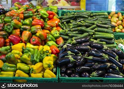 Vegetables in crates in supermarket. Arranged eggplants, peppers and zucchini.