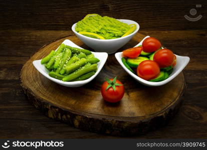 Vegetables on a dark wooden background. Salads, avocado, green beans.