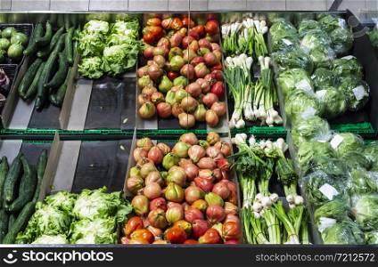 Vegetables on shelf in supermarket. Tomatoes, onion and lettuce.