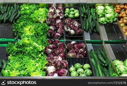 Vegetables on shelf in supermarket. Zucchini, cucumbers and lettuce.