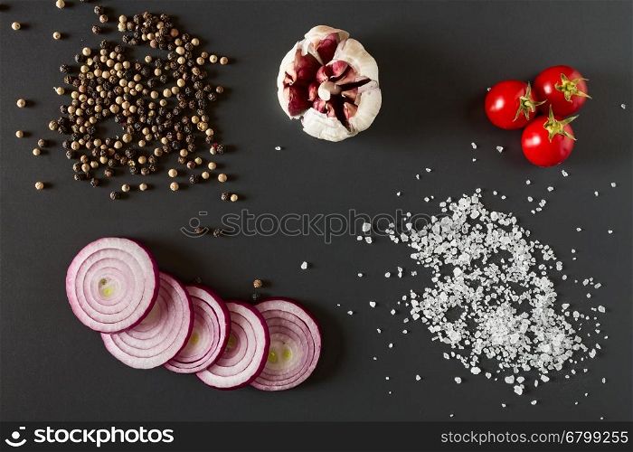 Vegetables, salt and pepper over a dark background seen from above