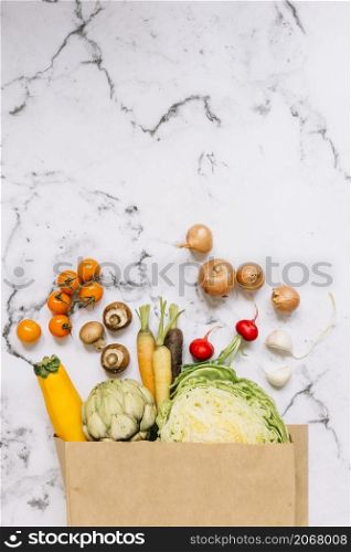 vegetables spill out from brown paper bag marble background