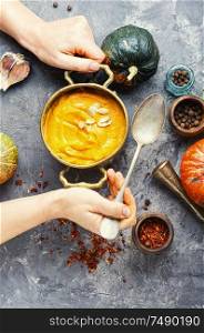 Vegetarian autumn pumpkin cream soup.Bowl of warm pumpkin soup in hands. Pumpkin vegan soup