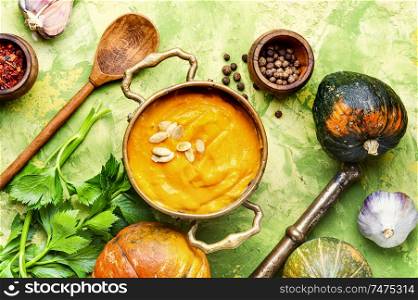 Vegetarian autumn pumpkin cream soup.Pumpkin soup and pumpkins. Pumpkin soup in a metal pot