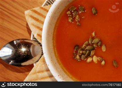 Vegetarian autumn pumpkin cream soup with pumpkin seeds and two pices of pita bread above view. Vegetarian autumn pumpkin cream soup with pumpkin seeds and two pices of pita bread