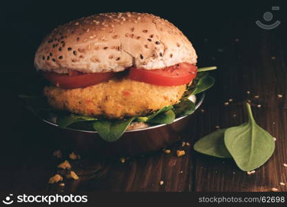 Vegetarian burger with carrot and quinoa on wooden table.