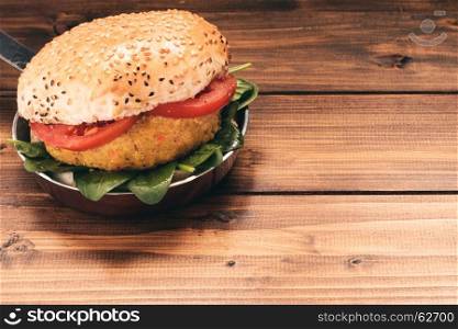 Vegetarian burger with carrot and quinoa on wooden table.