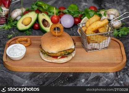 Vegetarian burger with french fries and salad on marble table