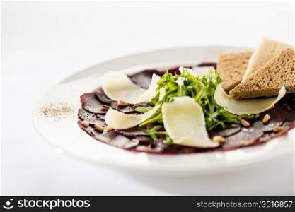 Vegetarian carpaccio with beetroot,nuts and toast on white background